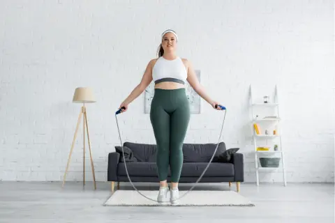 Frau springt Seil in einem Wohnzimmer. Sie fragt sich, wieviel bewegung pro woche ideal ist.