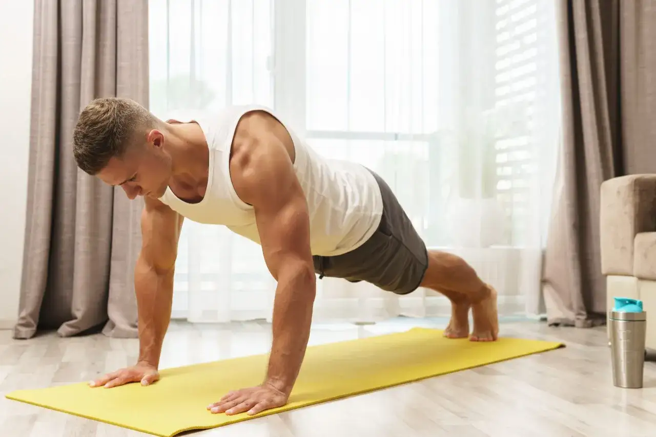 Mann macht Liegestütze auf einer gelben Matte. Effektives Krafttraining zu Hause für einen fitten Körper.