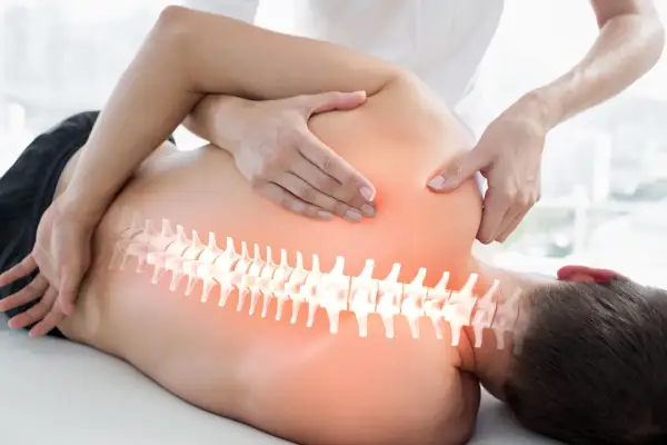Hände eines Therapeuten behandeln den Rücken eines Mannes. Die Wirbelsäule ist hervorgehoben. Ein visueller Hinweis auf den Unterschied zwischen Osteopathie und Chiropraktiker.